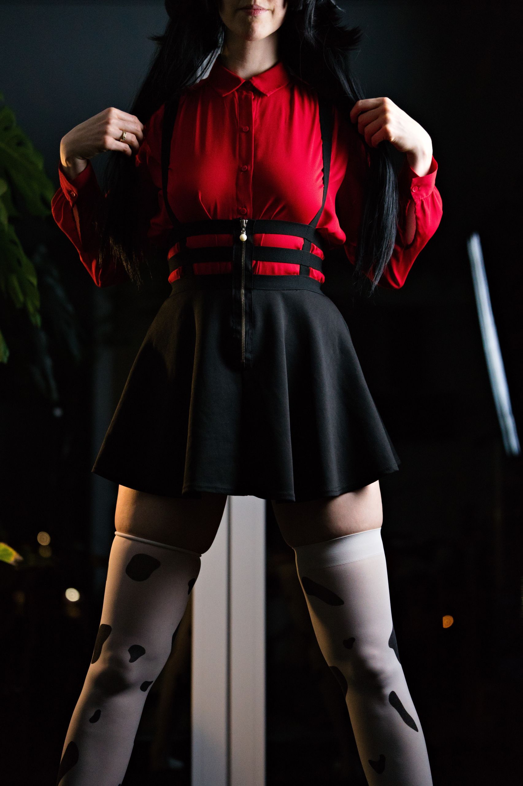 Shizuka Kawa cosplaying as Fuyuko Mayuzumi from Idolmaster wearing red shirt, black skirt with suspenders and cow-print stockings. Facing the camera and standing with legs spaced out. Focus on braless boobs under collared shirt and absolute territory created by skirt trim and cow-print stockings.